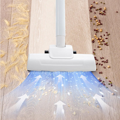 Vacuum cleaner head cleaning a wooden floor of home with debris.