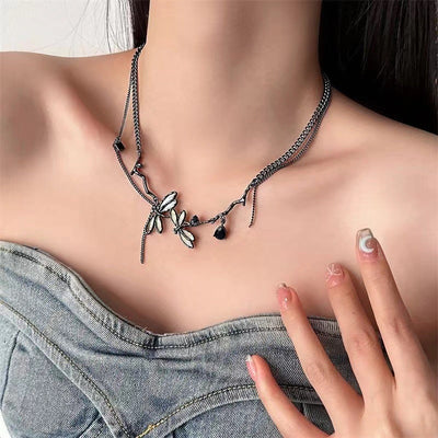 Necklace with butterfly pendants worn by a person, with a hand touching the necklace.